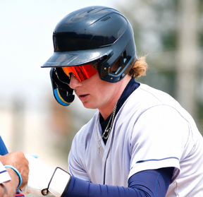 Baseball player wearing a helmet and Redrunner Cosmo sunglasses by Solaro Shades, preparing to hit a ball.