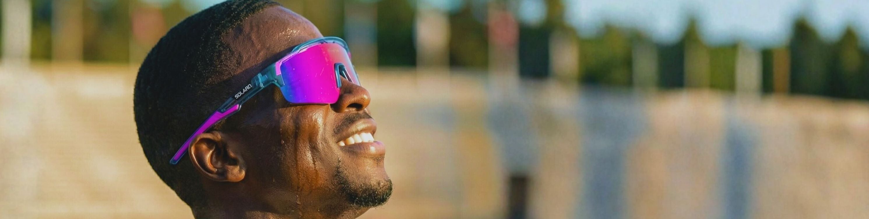 Person wearing colorful Solaro Shades sports sunglasses with a blurred natural.