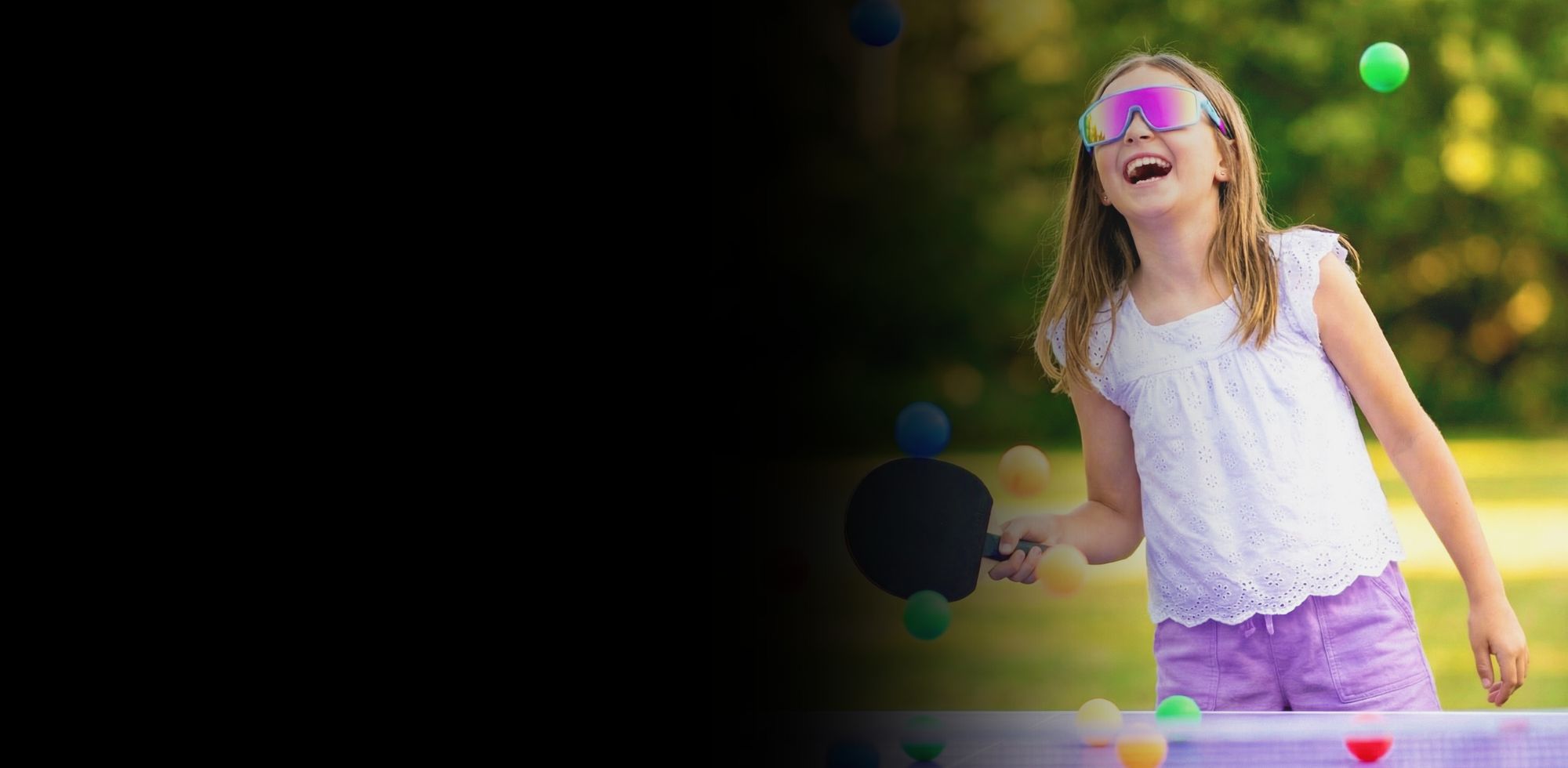 Child juggling colorful balls outdoors on a sunny day wearing Solaro Shades youth sunglasses. 