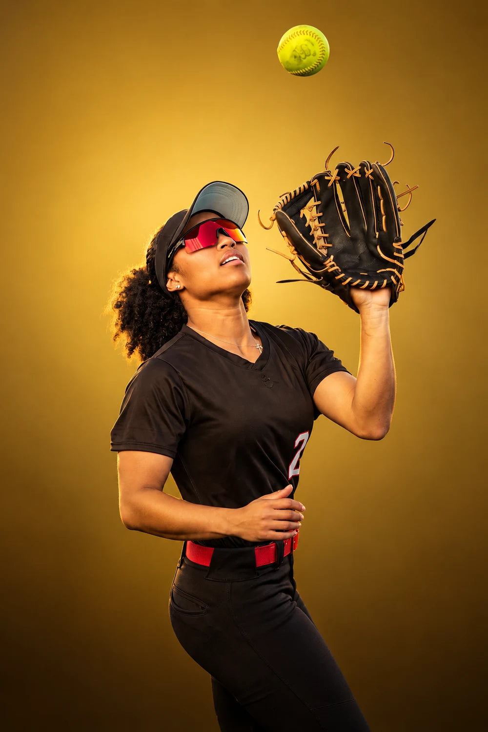 Softball athlete wearing red mirrored Solaro sunglasses, reaching up for a catch